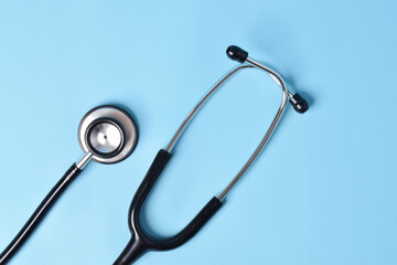 Stethoscope on light blue background, top view, closeup
