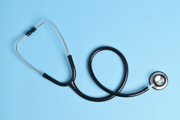 New stethoscope on light blue background, top view. Medical instrument