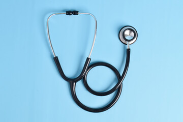 New stethoscope on light blue background, top view. Medical instrument