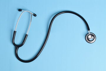 Black stethoscope isolated on a light blue background. flat lay, top view