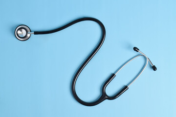 Black stethoscope isolated on a light blue background. flat lay, top view