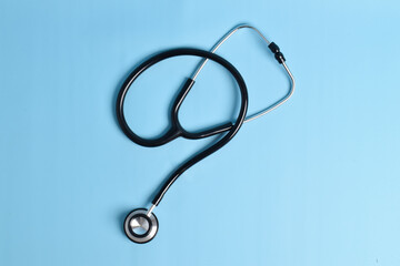 Black stethoscope isolated on a light blue background. flat lay, top view
