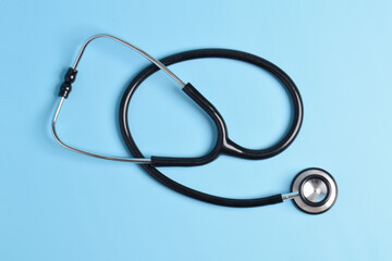 Black stethoscope isolated on a light blue background. flat lay, top view