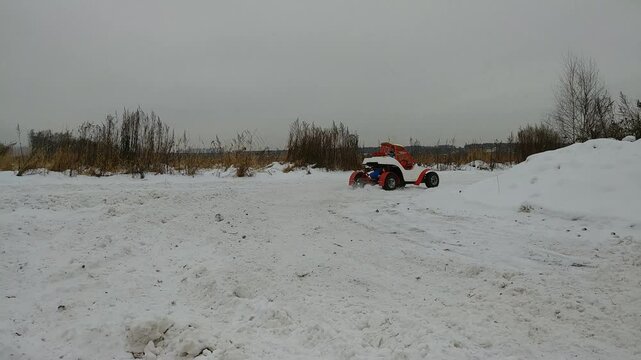Red and white toy car is sitting in the snow. A tire is missing from the car carting, karting, go-carting, karting