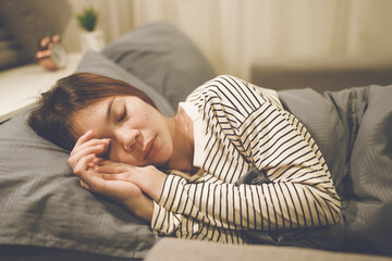 A tired woman wakes early with a headache, struggling with insomnia and fatigue. Low light, stress,...