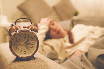 A tired woman wakes early with a headache, struggling with insomnia and fatigue. Low light, stress,...