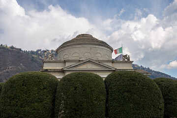 Historic Italian Monument with Flags Amidst a Scenic Mountain Backdrop