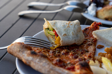 A triangle of pizza and burrito on plate