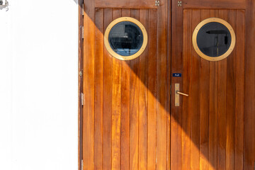 Detail of a wooden door with two portholes on the deck of a cruise ship