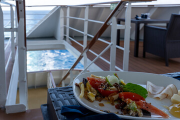 Plastic plate with salad on a table in the terrace of cruise ship