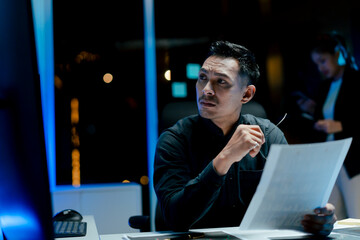 Portrait of a man working overtime at the office. Employee working hard, stressed, tired, working slowly.