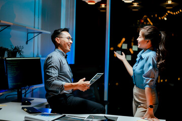 Male and female coworkers are working and analyzing projects in the office late at night.