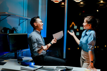 Male and female coworkers are working and analyzing projects in the office late at night.