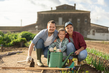 Family of farmers with a son in the garden after planting seeds. Generation of farmers grows...