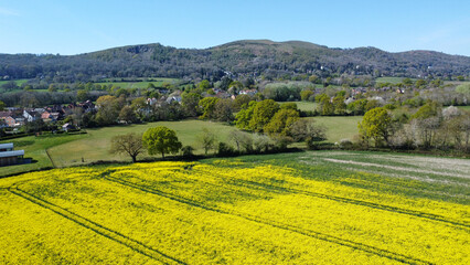 An aerial view of yellow rapeseed field in spring. With hills and countryside in the background. Malvern Hills, UK