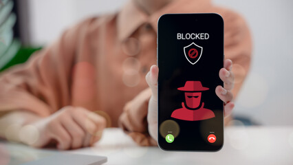 Phone screen showing scam call blocked with hacker icon and security shield. Concept of mobile protection, cybercrime prevention, caller ID alert system, and digital safety awareness.