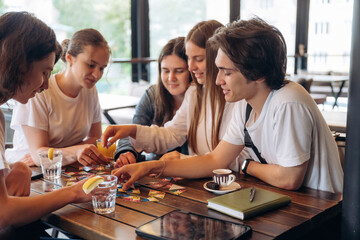 Wellness, playing card game. Group of young friends are in the cafe restaurant