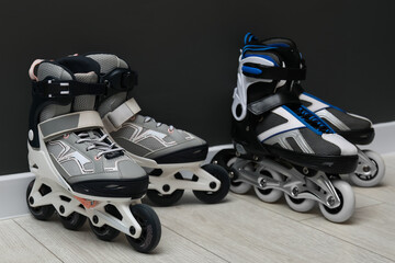 Pairs of roller skates on floor near black wall