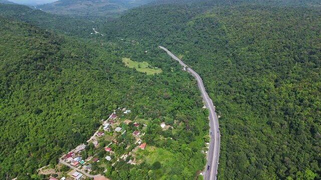 Drone footage of the aerial view of a winding road cutting through lush green forest. Scenic highway number 304 in Thailand links the Bangkok area to Nakhon Ratchasima in the northeastern region