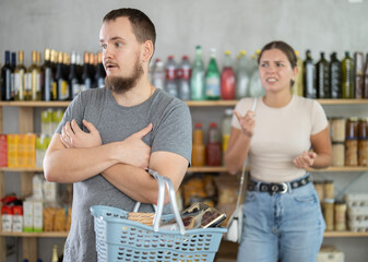 Wife stands behind husband and yells at companion. Angry man is silent and ignores womans...