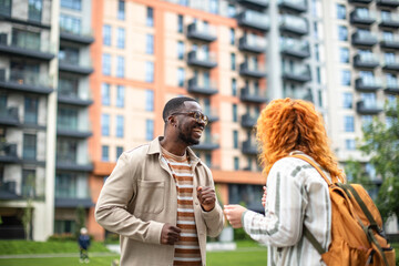Couple enjoying a lighthearted conversation in front of an apartment building on a sunny afternoon