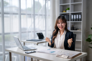 Excited businesswoman celebrating success at office desk