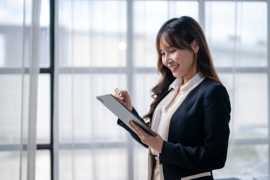 Smiling businesswoman using digital tablet and stylus in modern office