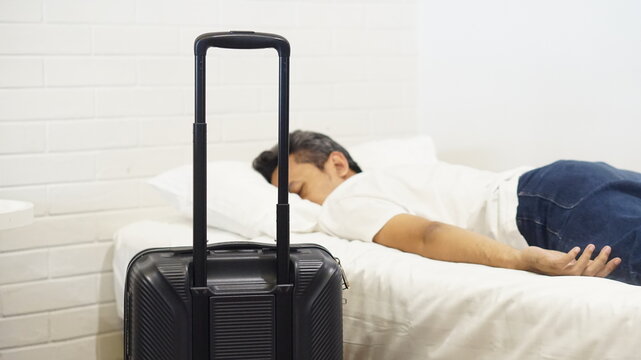a man sleeping on a comfortable bed in a hotel room after arriving from a trip