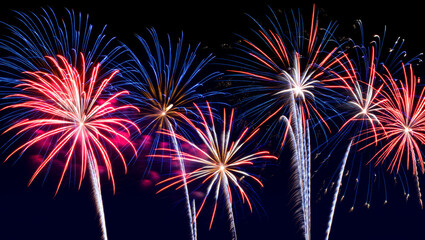 Vibrant red, white, and blue fireworks display exploding in a dark night sky for a festive celebration