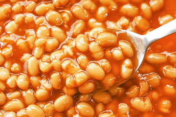 Baked beans in tomato sauce on spoon.