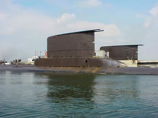 Modern Submarine Docked at Port on Calm Water under Blue Sky

