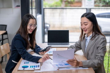 Obraz premium Businesswomen working together analyzing charts and financial data in office