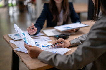 Businesswomen working together analyzing financial charts and documents at office desk