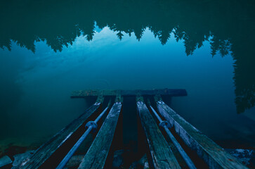 Dark ominous light casts reflections on a quiet evening lake by the reservoir, moody atmosphere