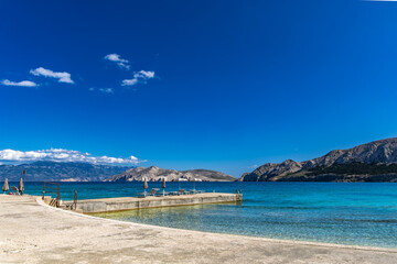 Concrete pier in Baska on the island of KRK, a restaurant on the pier, sun umbrellas and restaurant...