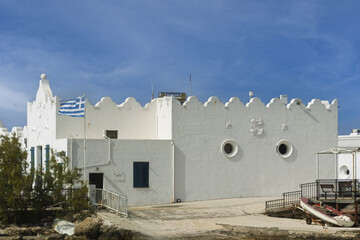 Bas-relief sculpture depicting an anchor with a chain wrapped around its vertical axis, two whales, and small stars on an old building in the port of Mandraki in Rhodes, Greece