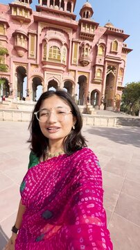 4K vertical selfie video of Indian woman wearing saree and vlogging while standing at Patrika Gate in Jaipur, Rajasthan, India. Travel blogger making content on location. Old Indian architecture.