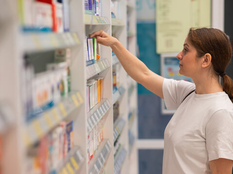 Caucasian woman choosing medicines in a pharmacy.  - Powered by Adobe