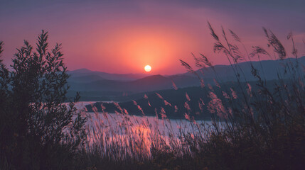 Stunning sunset paints the sky with vivid hues over a tranquil lake and mountains.