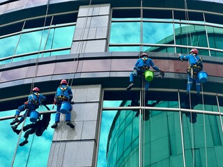 Worker climbing to clean glass windows — a high-rise maintenance task that highlights the skill and risk involved in urban building upkeep. Tanah Abang, Jakarta - June 16, 2025