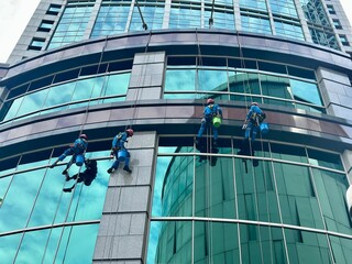 Worker climbing to clean glass windows — a high-rise maintenance task that highlights the skill...