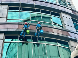 Two workers climbing to clean glass windows — a high-rise maintenance task that highlights the...