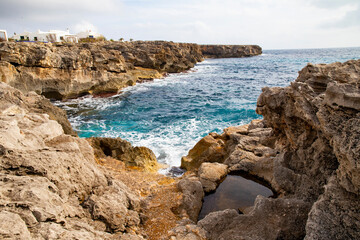 white houses on the cliffs. Living by the sea. Majestic cliffs and waves on the coast of Menorca, Spain
