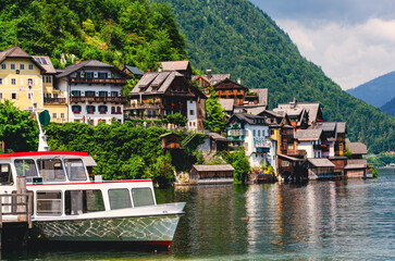 Hallstadt in Austria. A boat is docked in front of a house. The house is surrounded by trees and has a green roof