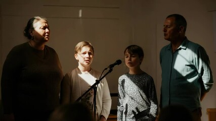 Diverse family of two adults, children singing on stage with microphone