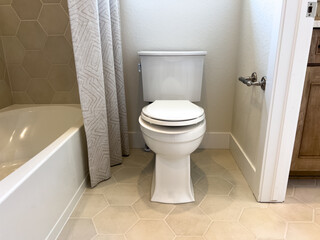 Toilet next to bathtub with modern tile