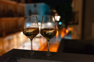 Two glasses of wine on the balcony ledge of a hotel in the summer evening, at night. Vacation time.