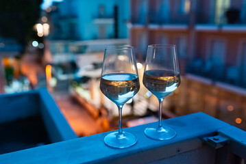 Two glasses of wine on the balcony ledge of a hotel in the summer evening, at night. Vacation time.