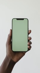 Hand holding smartphone with green blank screen on white background