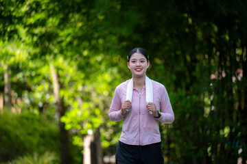 A woman is walking in a park with a towel around her neck